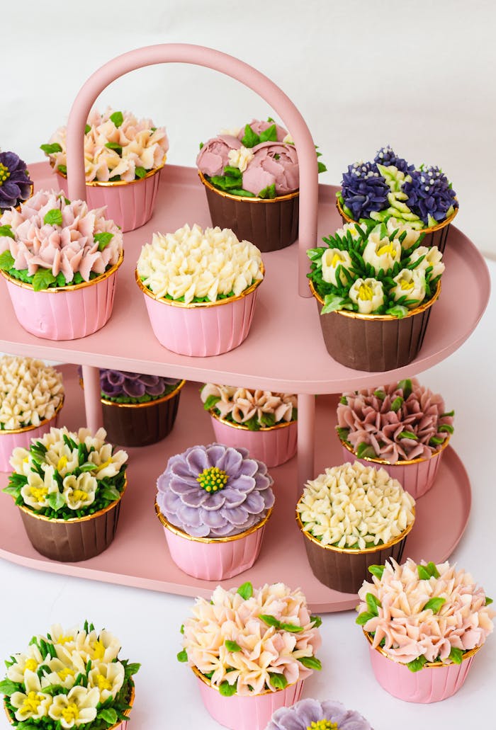 A beautifully arranged floral cupcake display on a pink tiered stand, perfect for celebrations.