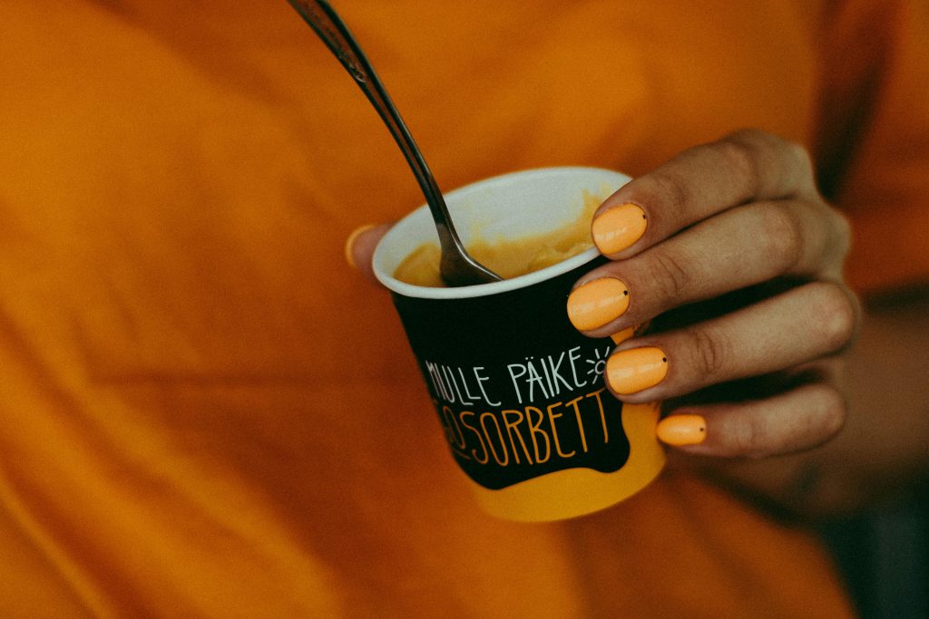 pexels photo 2262048 2262048 Close-up of a hand holding refreshing mango sorbet with orange nails.