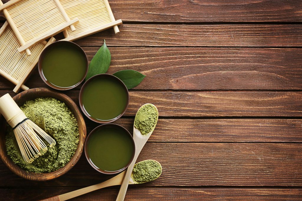Matcha et boissons florales : découvrez leurs vertus pour le corps et l’esprit Top view of traditional matcha tea setup with utensils on a wooden table, showcasing a blend of culture and flavor.