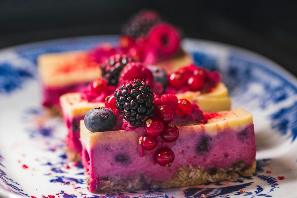 pexels photo 827513 827513 Sliced berry cheesecake topped with vibrant fresh berries and served on a decorative plate.