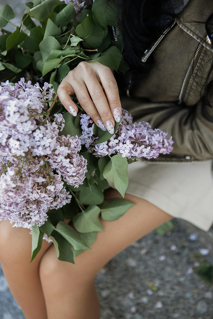 A woman gently holds a lilac bouquet, showcasing intricate details and natural beauty.