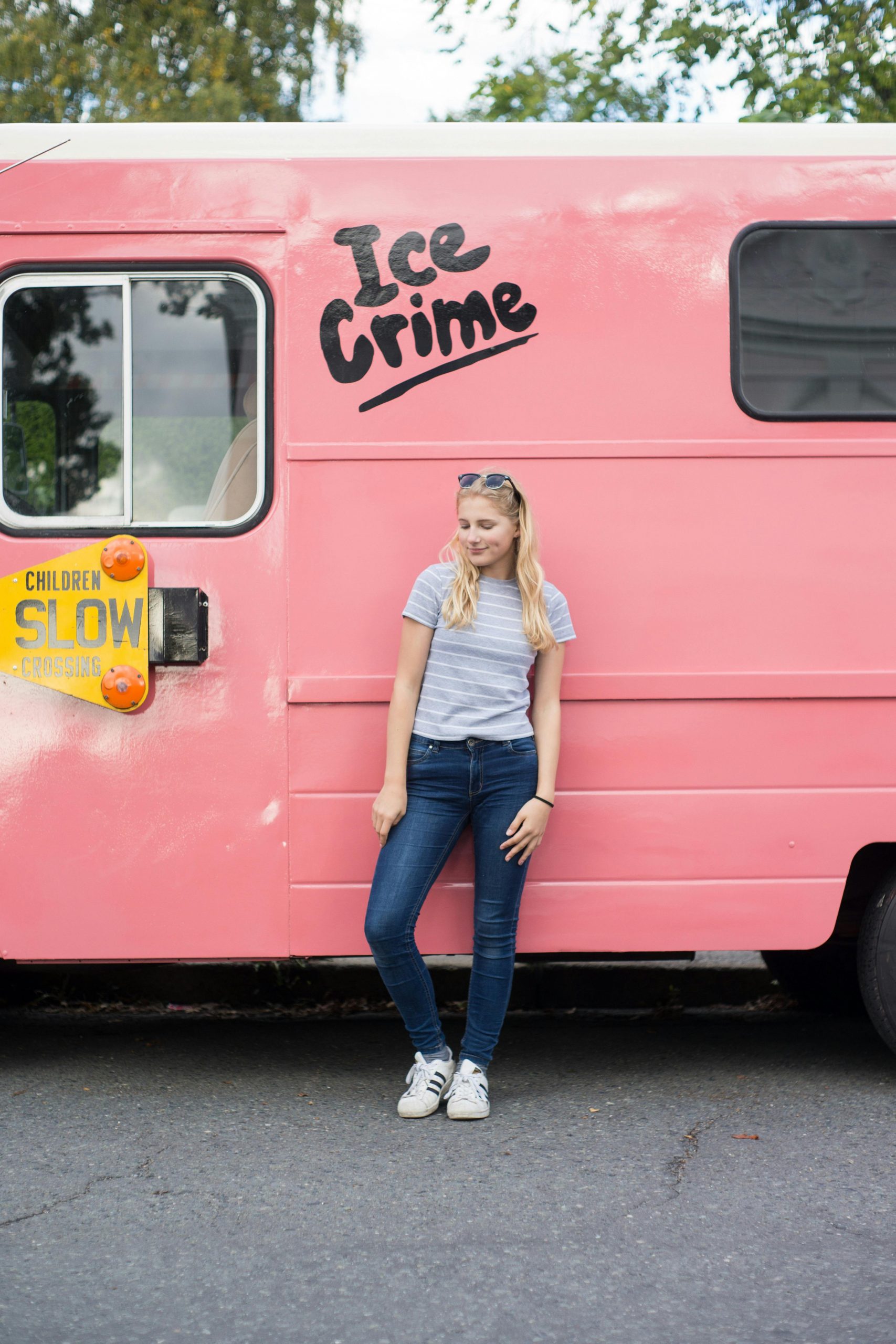 Teen girl leaning on a pink ice cream truck in urban Oslo, Norway.